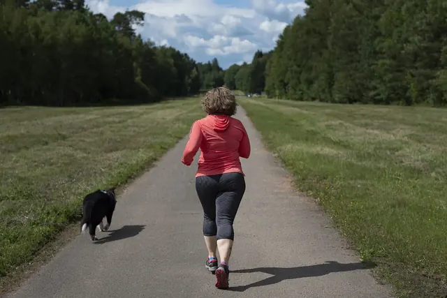 Juoksija juoksee maaseudun polulla koiran juostessa vierellä