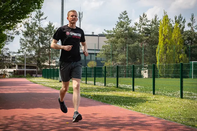 Juoksija harjoittelee juoksuradalla puiden reunustamalla kentällä